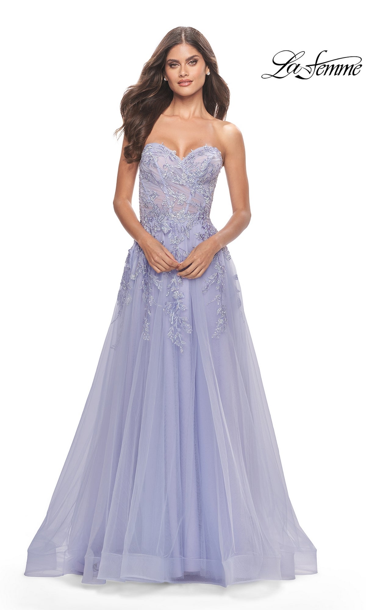 A woman models the La Femme Strapless Sweetheart Long Prom Dress 31363 in lavender with lace floral embroidery and a tulle overlay, standing against a white background. The